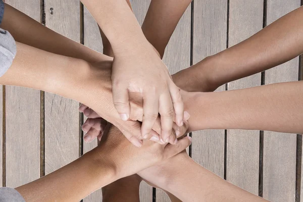 Personnes mettre la main ensemble sur la table en bois pour une utilisation comme équipe con — Photo