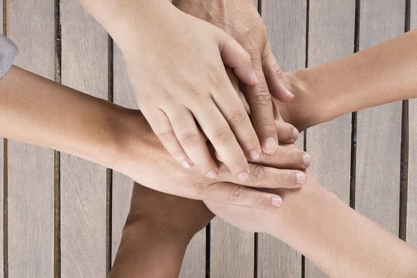 Persone mettere mano insieme sul tavolo di legno per l'uso come lavoro di squadra con — Foto Stock