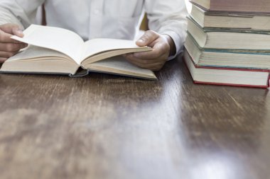 adam ahşap masa üzerinde ders kitabı deste ile kitap okuma