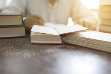 adam ahşap masa üzerinde ders kitabı deste ile kitap okuma