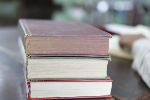 man reading book with textbook stack on wooden desk