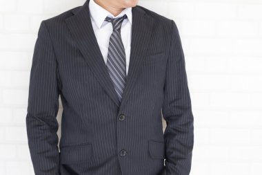 Beyaz duvarın yanında duran takım elbiseli iş adamı