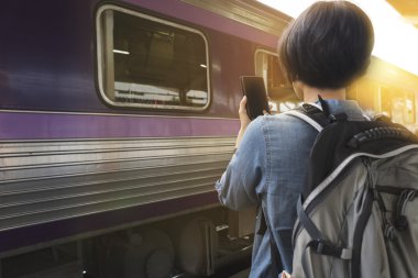 Smartphone sırt çantası ile tren istasyonunda tutan kadın