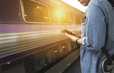 Smartphone sırt çantası ile tren istasyonunda tutan kadın
