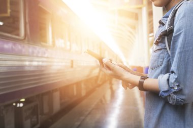 Smartphone sırt çantası ile tren istasyonunda tutan kadın