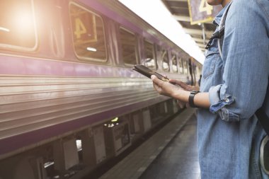 Smartphone sırt çantası ile tren istasyonunda tutan kadın