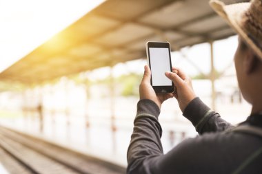 Smartphone sırt çantası ile tren istasyonunda tutan adam