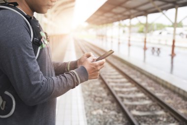 Smartphone sırt çantası ile tren istasyonunda tutan adam