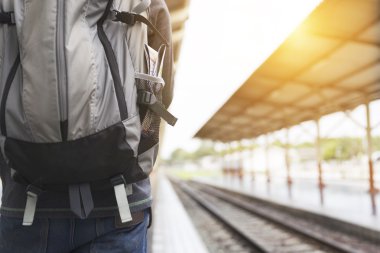 Tren istasyonunda sırt çantalı bir adam var.