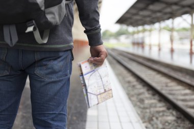 sırt çantası ile harita tren istasyonunda tutan adam