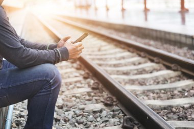 Tren istasyonunda elinde akıllı telefon tutan adam.