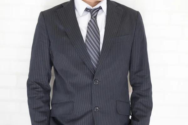 Businessman in suit standing beside white wall — Stock Photo, Image