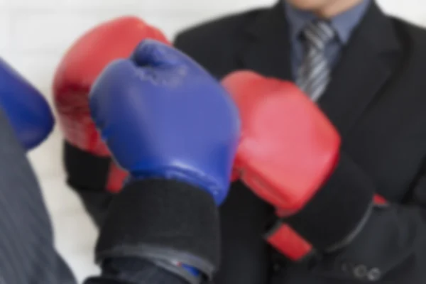 Hombre de negocios en traje con guantes de boxeo rojos y azules perforando cada uno — Foto de Stock