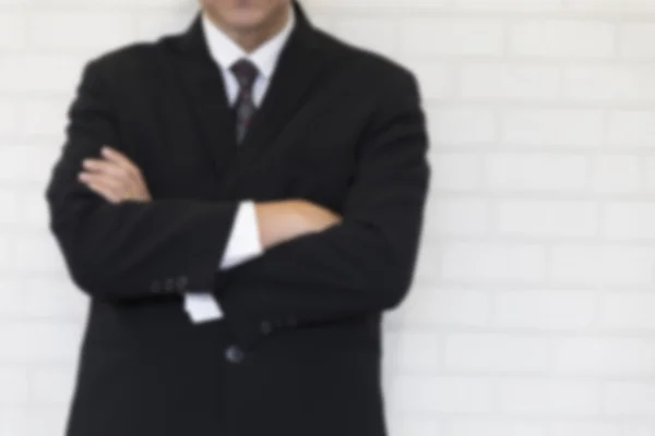 Uomo d'affari in giacca e cravatta incrociato il braccio accanto al muro bianco - sfocatura per — Foto Stock