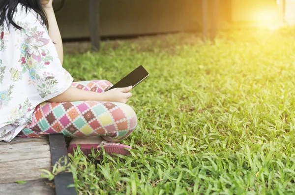 girl holding tablet sitting on lawn yard