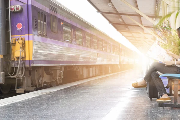 Kvinna med karta sitter bredvid järnvägen i tågstation — Stockfoto