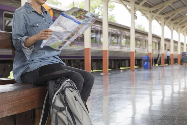 Kvinna med karta med ryggsäck på tågstationen — Stockfoto