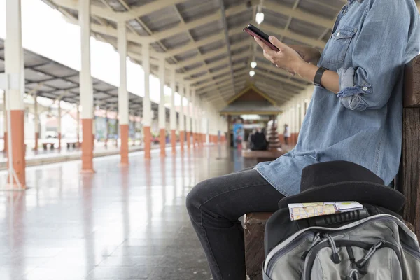 Vrouw met smartphone met rugzak op station — Stockfoto