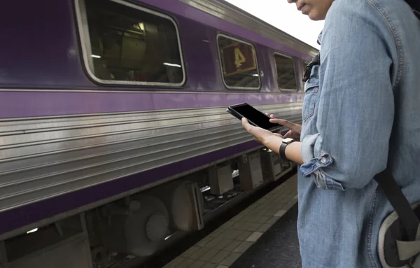 Kvinna med smartphone med ryggsäck på tågstationen — Stockfoto