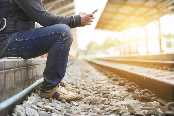 Mann hält Smartphone am Bahnhof — Stockfoto