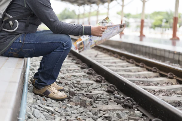 Homem segurando mapa com mochila na estação de trem — Fotografia de Stock