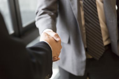 Takım elbiseli işadamları pencerenin yanında el sıkışıyor - iş ekibi