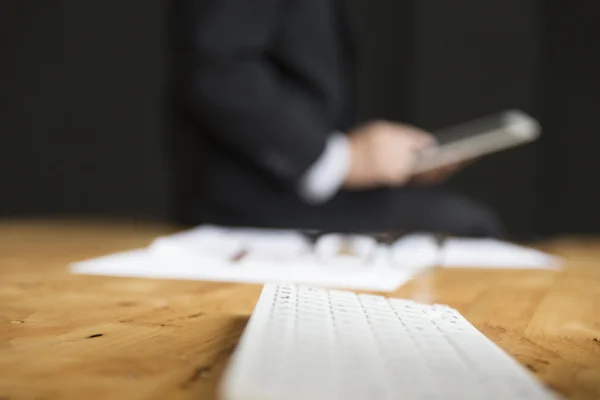 Teclado de la computadora con el fondo del hombre de negocios en traje usando t — Foto de Stock