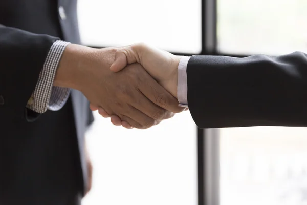 Hombres de negocios en traje estrechando la mano al lado de la ventana - equipo de negocios —  Fotos de Stock