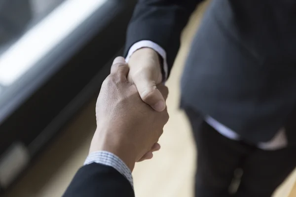 Hombres de negocios en traje estrechando la mano al lado de la ventana - equipo de negocios —  Fotos de Stock