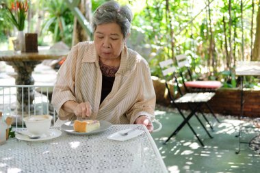 Yaşlı Asyalı yaşlı yaşlı yaşlı kadın restoranda cheesecake yiyor. olgun emeklilik yaşam tarzı