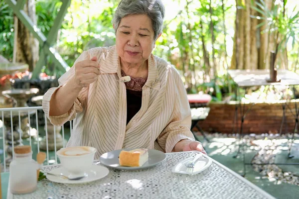 在餐馆吃芝士蛋糕的年老的亚裔老年老妇人 成熟的退休生活方式 — 图库照片