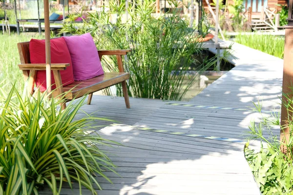花园公园的绿叶装饰在木制长椅旁边 — 图库照片
