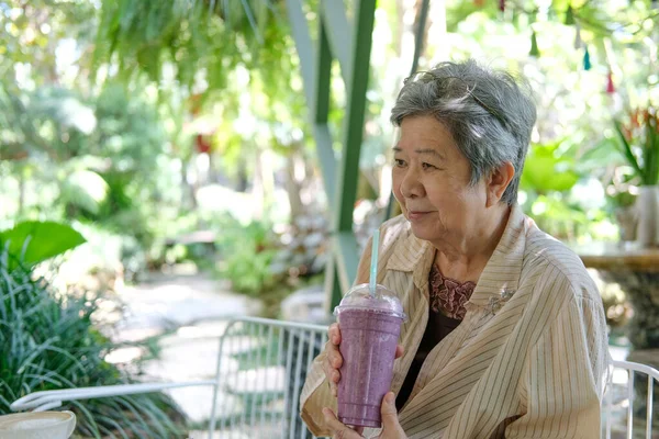 在餐馆里 年长的亚裔老年老年妇女喝着浆果软糖酸奶奶昔 成熟的退休生活方式 — 图库照片