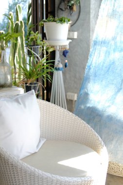 Evdeki terasta beyaz hasır koltuk.