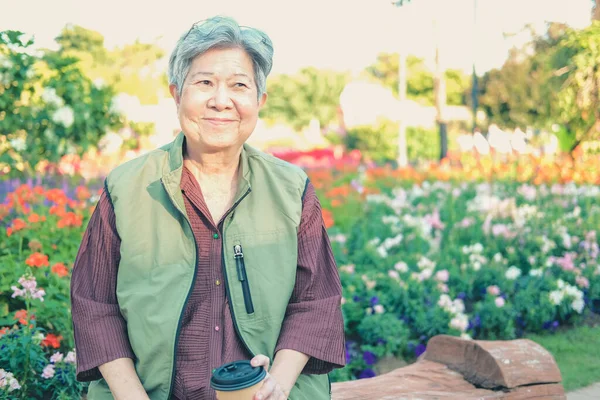 庭でコーヒーを飲むアジア系のお年寄り女性 シニアレジャーライフスタイル — ストック写真