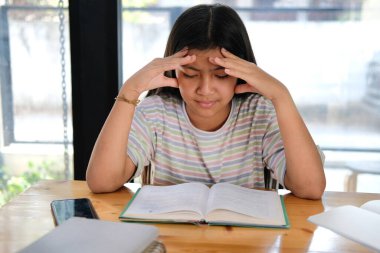 Asyalı kız öğrenci çok çalışıyor. Stres altında. Sıkıntıdan patlıyor. çocuk eğitimi