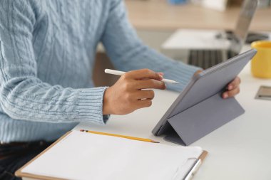 Asyalı genç öğrenci genç girişimci. Tabletle çalışıyor. Evde internetten öğrenim görüyor. Webinar toplantısını öğreniyorum. Covid salgınında sosyal uzaklık