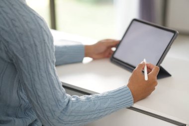 Asyalı genç öğrenci genç girişimci. Tabletle çalışıyor. Evde internetten öğrenim görüyor. Webinar toplantısını öğreniyorum. Covid salgınında sosyal uzaklık