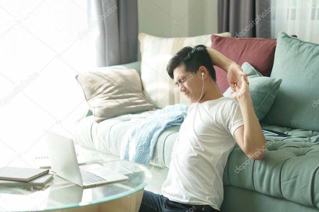 asian young student man teenager entrepreneur wear earphones stretching feeling tired bored sleepy while working with computer studying learning online at home. e-learning education