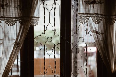 Cam pencerenin yanında bej el yapımı pamuklu örgü perdesi