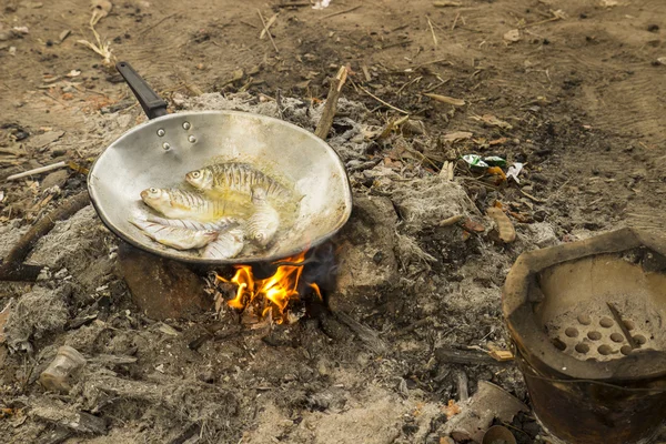 Приготовление жареной рыбы в лагере — стоковое фото