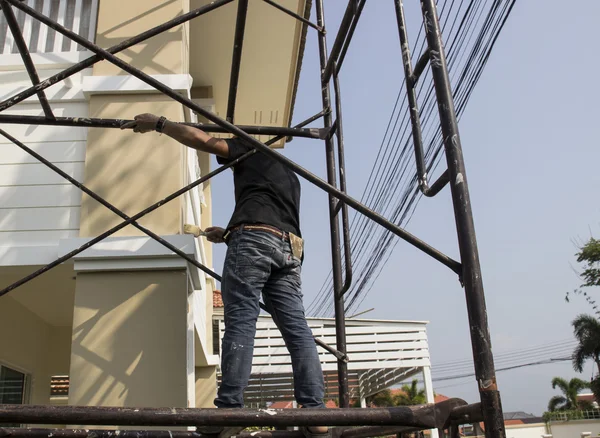 Worker on scaffold painting wall — Stock Photo, Image