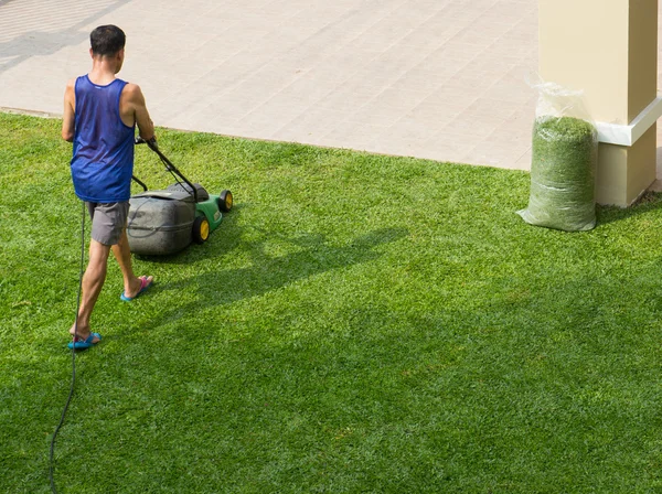 Pracownik za pomocą Kosiarki do wykończenia trawa trawnik — Zdjęcie stockowe
