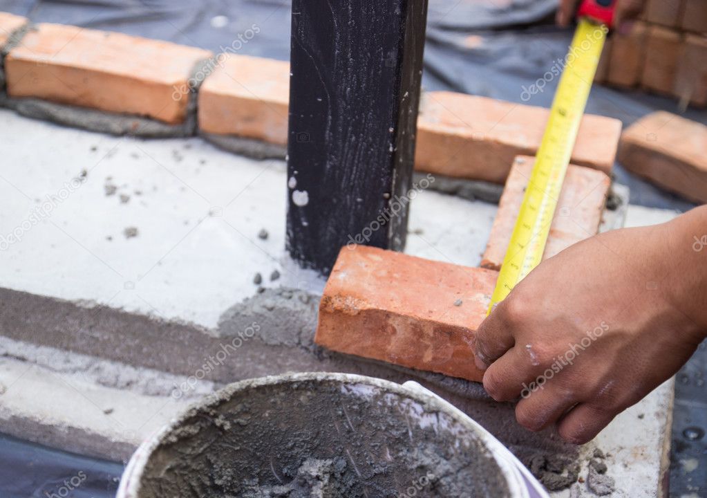 the worker is measuring the brick