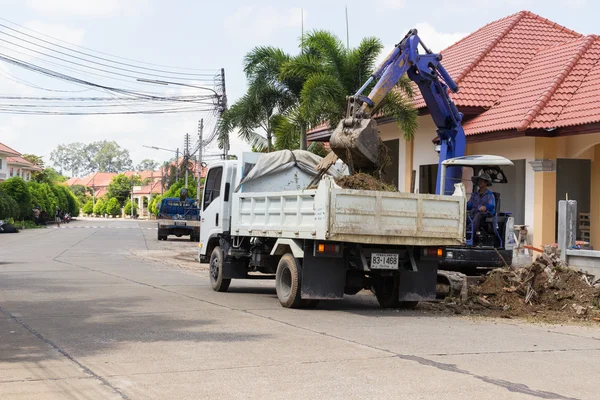 The worker controls the backhoe shovel to unload the earth on th — Stock Photo, Image