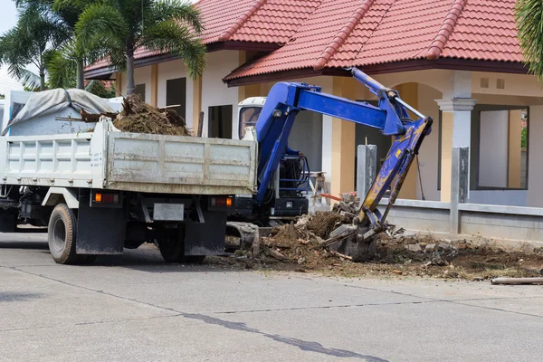 The worker controls the backhoe shovel to load the earth on the — Stock Photo, Image