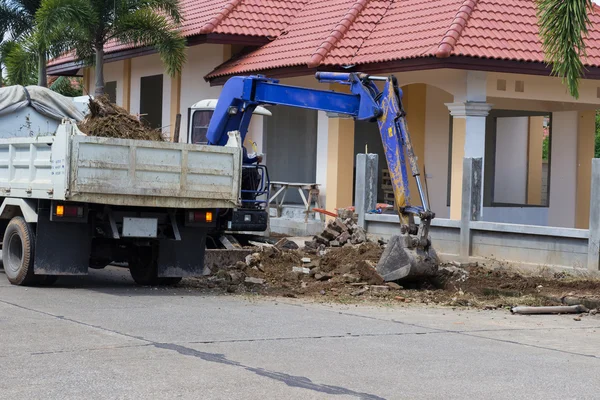 The worker controls the backhoe shovel to load the earth on the — Stock Photo, Image