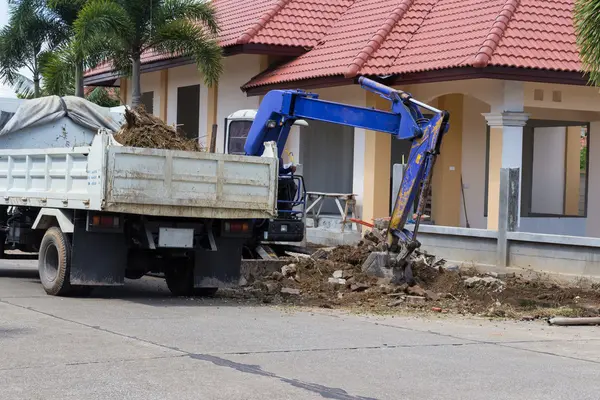 The worker controls the backhoe shovel to load the earth on the — Stock Photo, Image