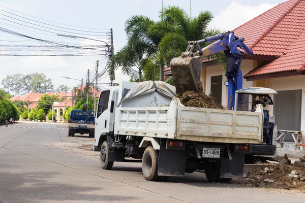 The worker controls the backhoe shovel to unload the earth on th — Stock Photo, Image