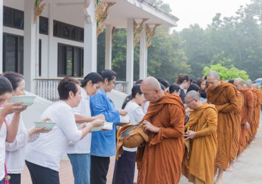 İnsanlar gıda teklifleri yapmak için bir Budist keşiş 's sadaka kase koyun.